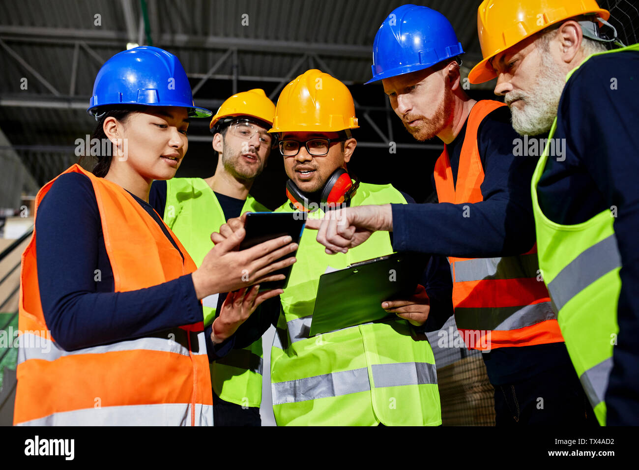 Workers in factory warehouse talking and using tablet Stock Photo