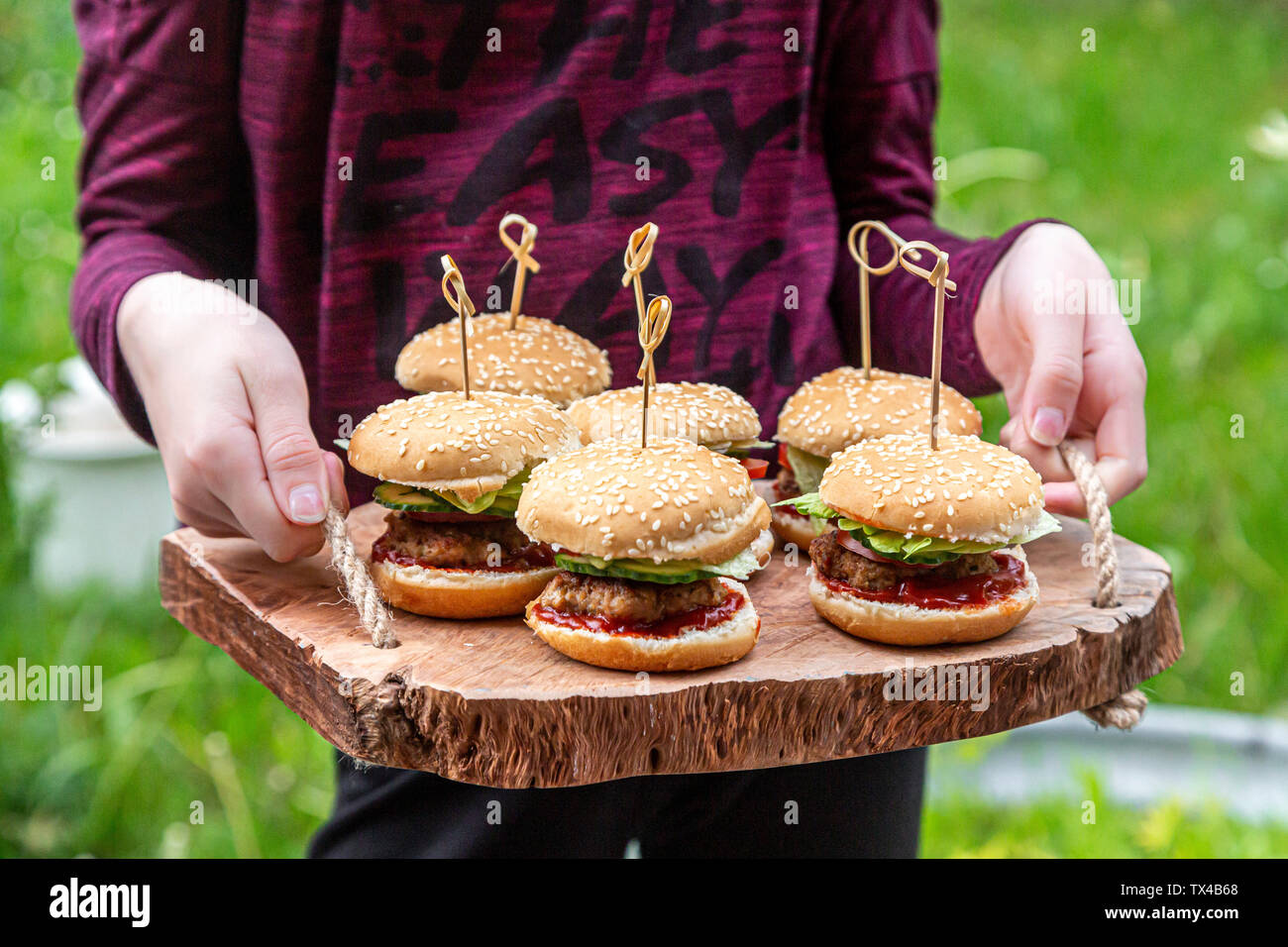 Girl holding wooden tray with mini burger Stock Photo Alamy