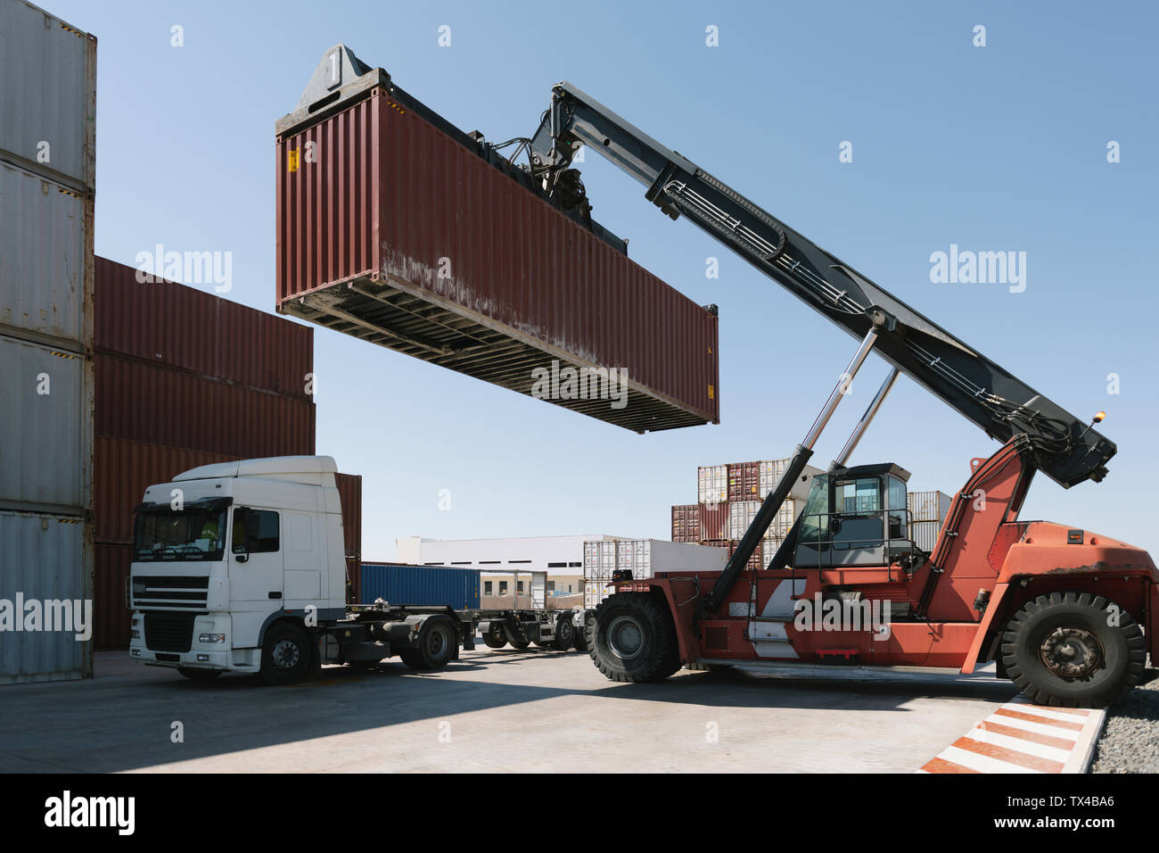 Crane lifting cargo container on truck on industrial site Stock Photo