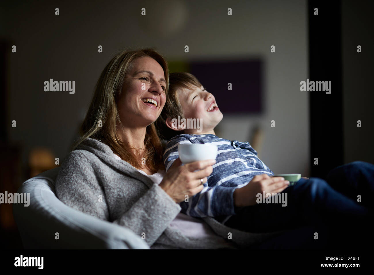Mother and son sitting in arm cahir, laughing Stock Photo