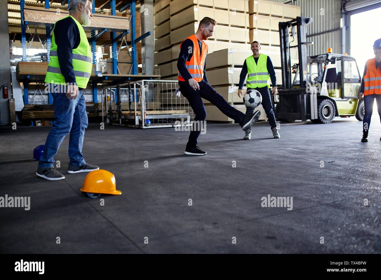 Workers playing football in factory warehouse Stock Photo Alamy
