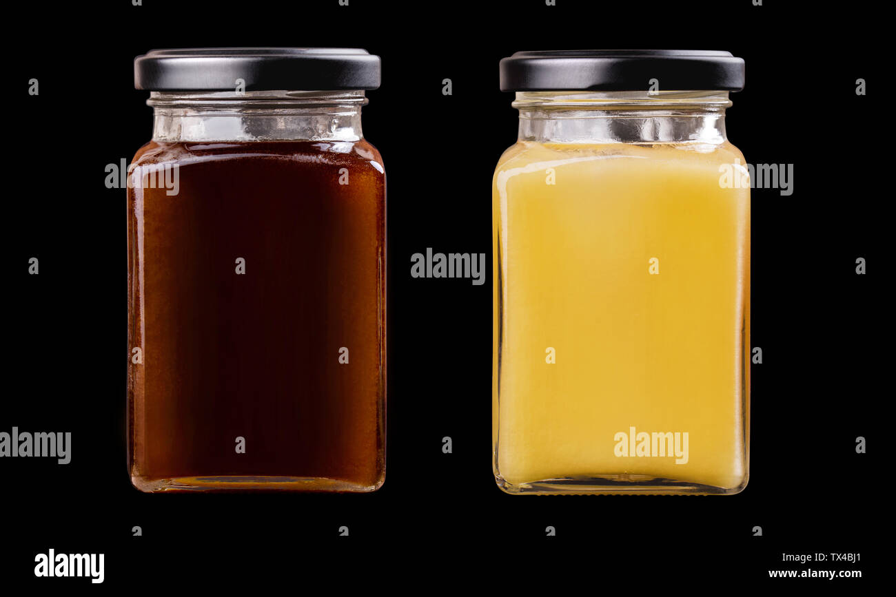 Two jars with white honey souffle and black honey isolated on black