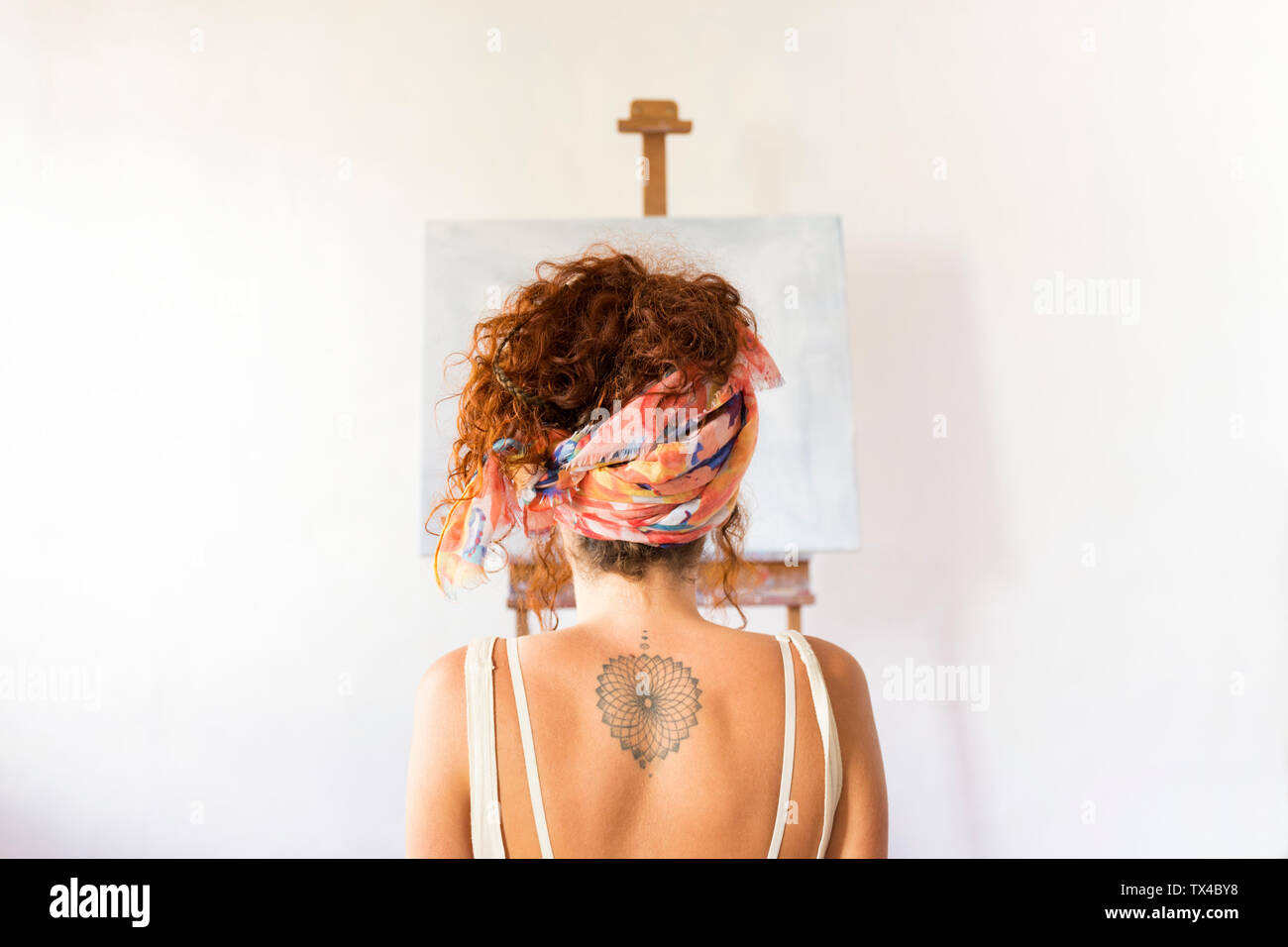 Rear view of young female painter in art studio in front of empty canvas Stock Photo