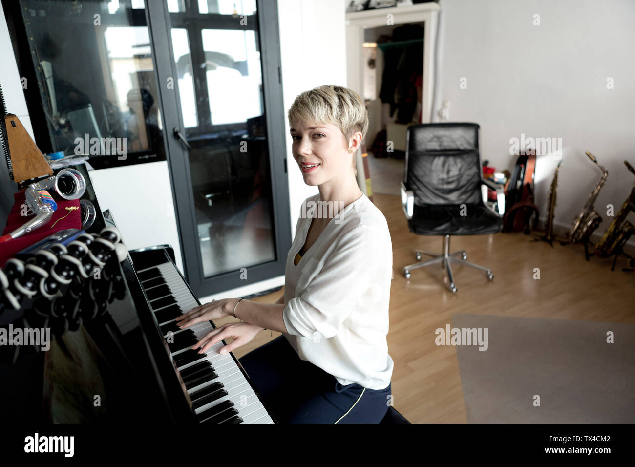Portrait of smiling woman playing piano in her music room Stock Photo