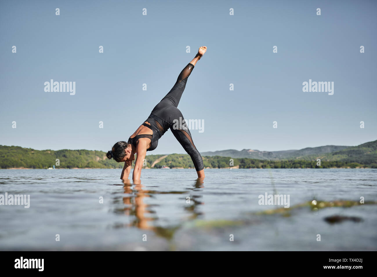 Young woman doing yoga in nature, downward facing dog pose Stock Photo