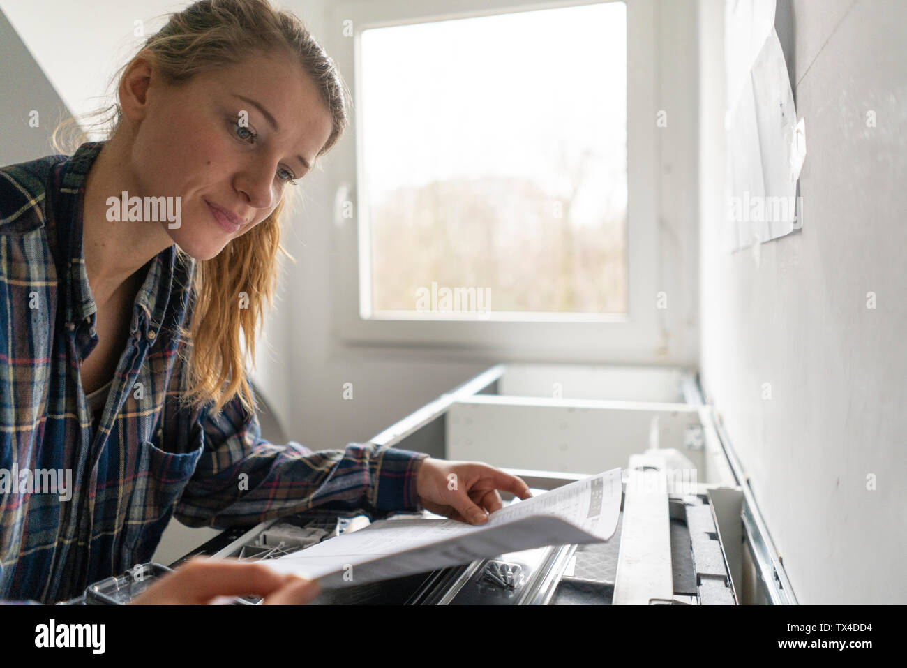 Young woman studying assembly instructions in kitchen Stock Photo - Alamy