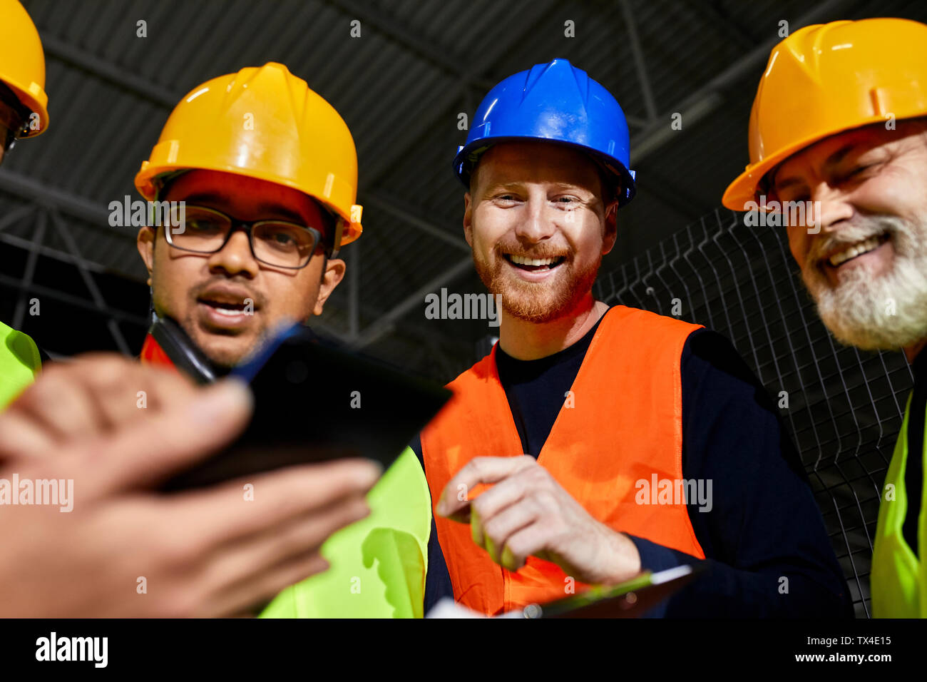 Happy workers in factory warehouse talking and using tablet Stock Photo