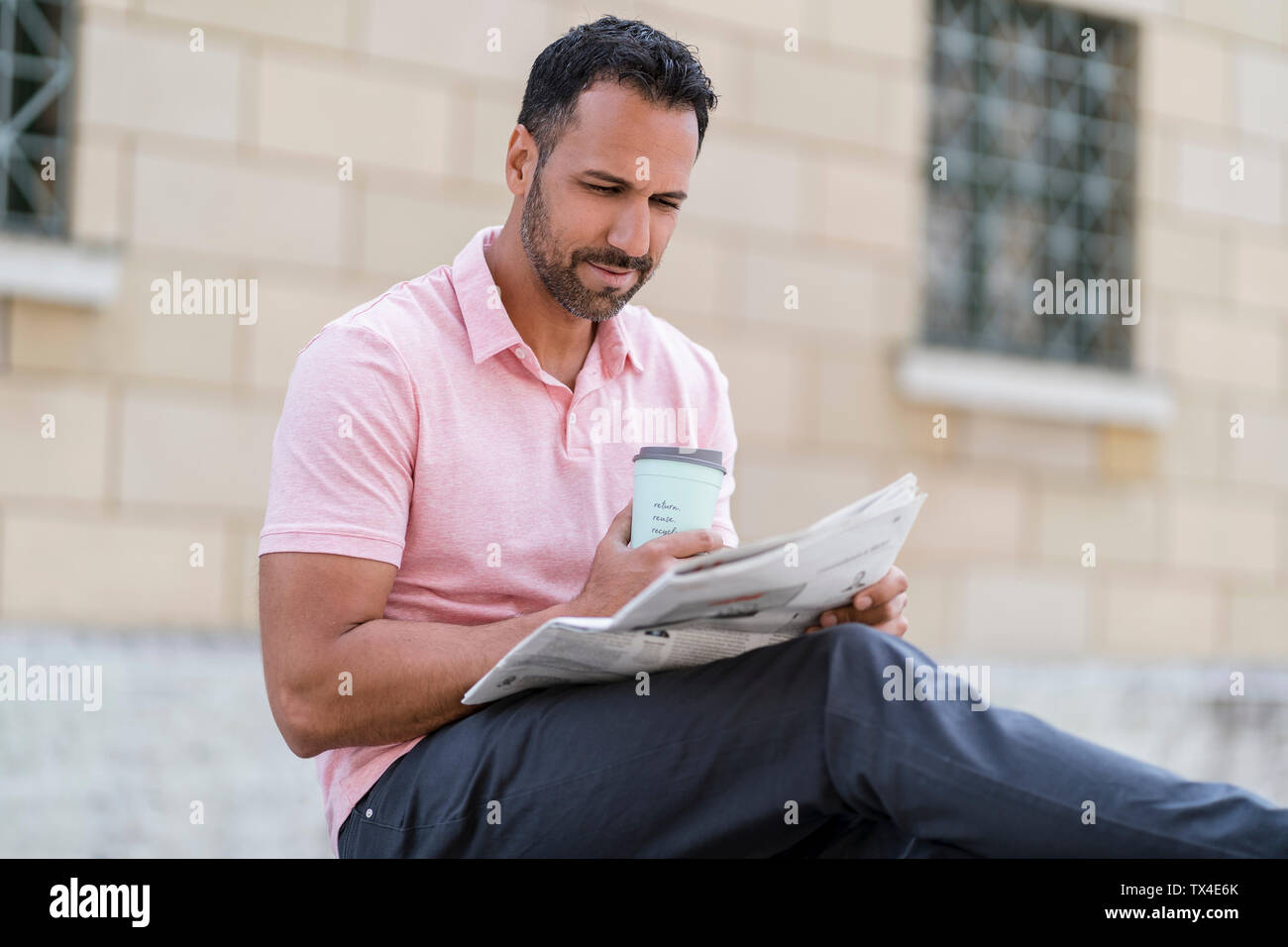 Man with takeaway coffee reading newspaper in the city Stock Photo
