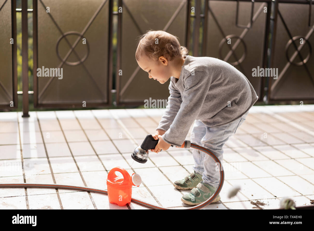Cutle little girl filling water into watering can Stock Photo