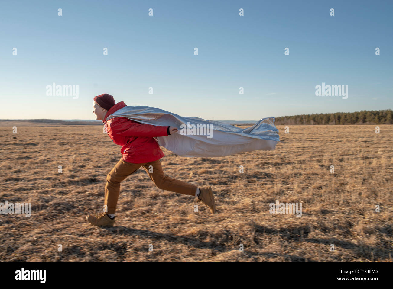 Happy boy dressed up as superhero running in steppe landscape Stock Photo