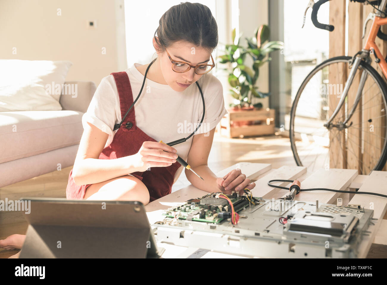 Young woman working on computer equipment at home next to tablet Stock Photo