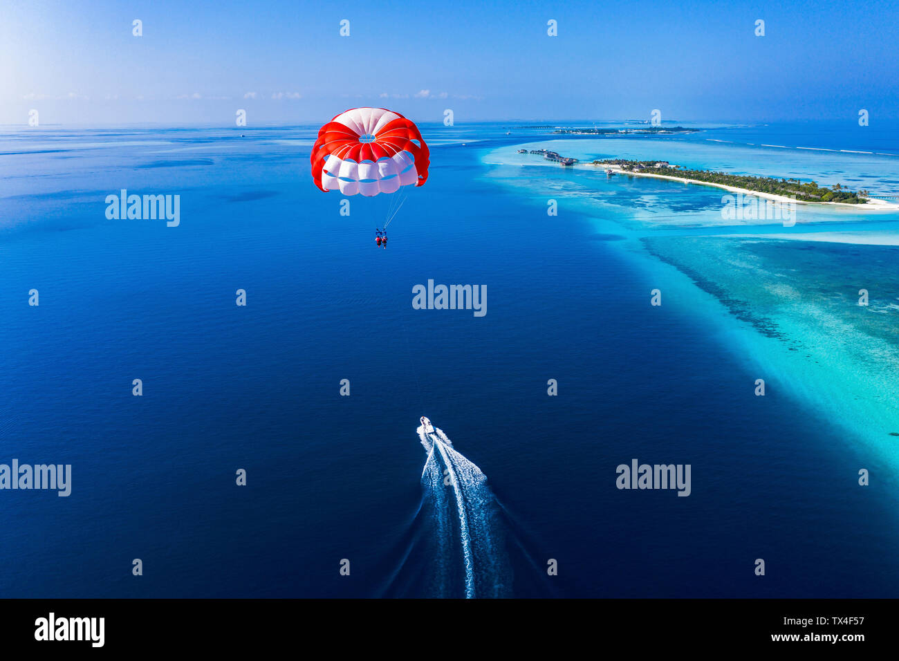 Maledives, South Male Atoll, paraglider flying along an atoll, aerial view Stock Photo