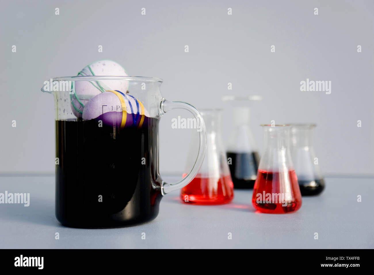 Eggs dyed with rubber bands and purple natural colour in measuring flask Stock Photo