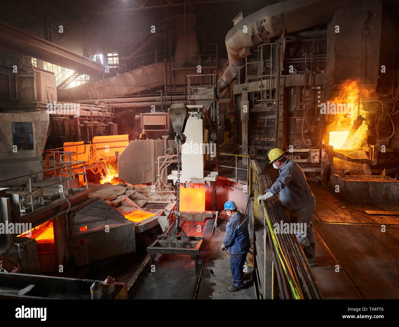 Industry, Worker lifting copper plates with indoor crane for cooling in water basin Stock Photo