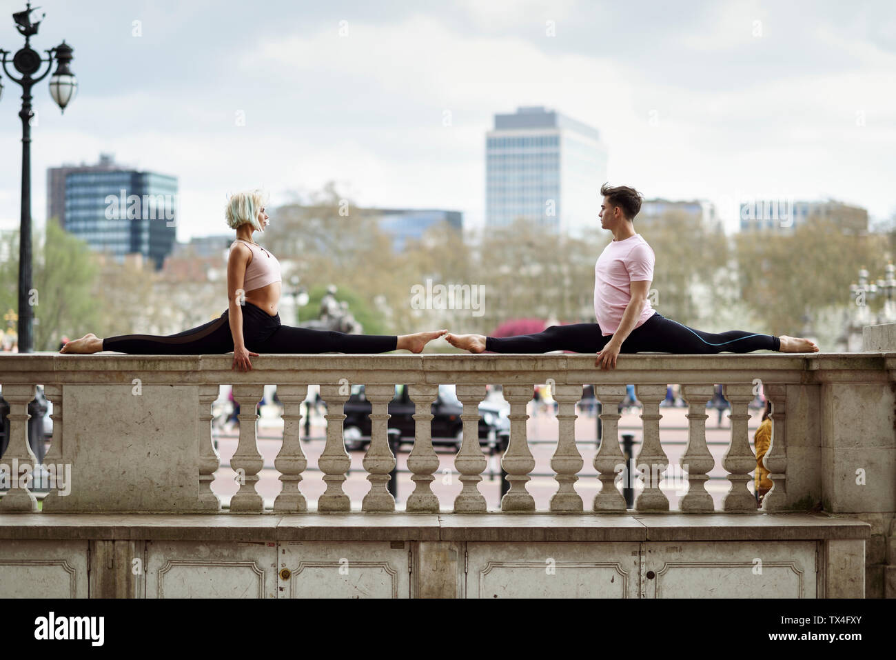 UK, London, young couple doing gymnastic acrobatics on parapet at Buckingham Palace Stock Photo