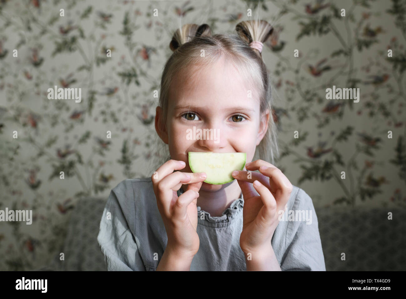Portrait of blond girl with slice of courgette Stock Photo