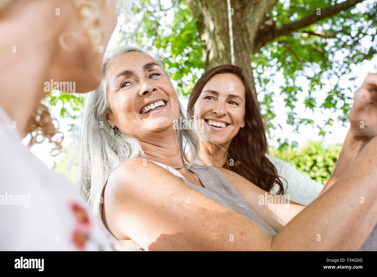Women of a family relaxing in garden, sitting on a swing bed Stock Photo