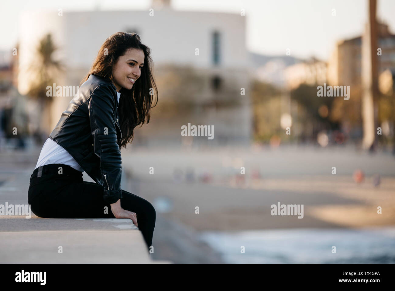 Side view of woman sitting on wall by the beach hi-res stock ...