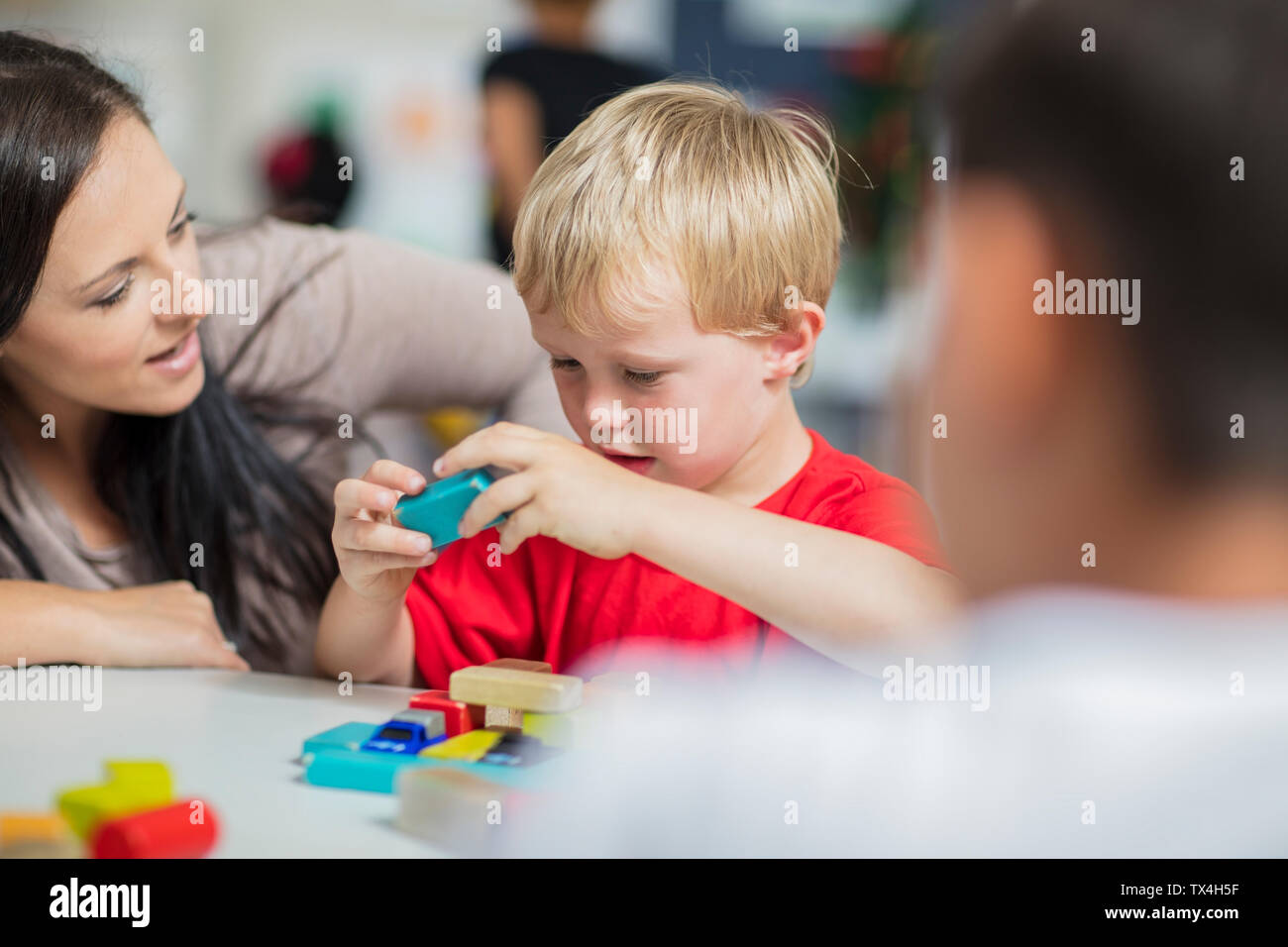 Pre-school teacher playing with child in kindergarten Stock Photo