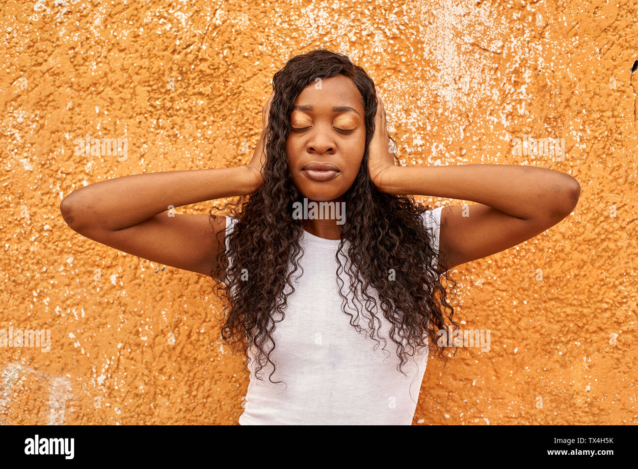 Portrait of young woman covering  ears with her hands Stock Photo