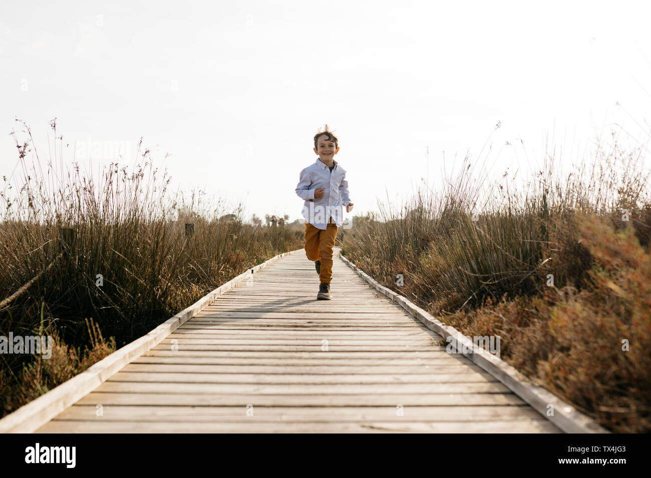 Happy little boy running on boardwalk Stock Photo