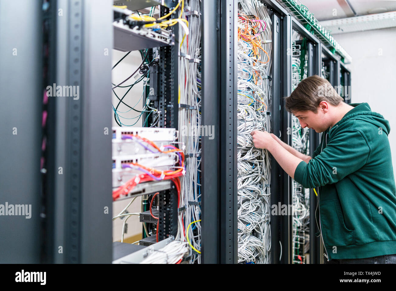 Teenager working with cables in server room Stock Photo