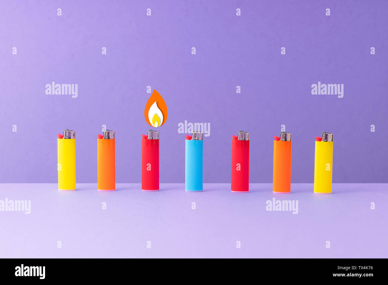 Row of colorful lighters against purple background Stock Photo