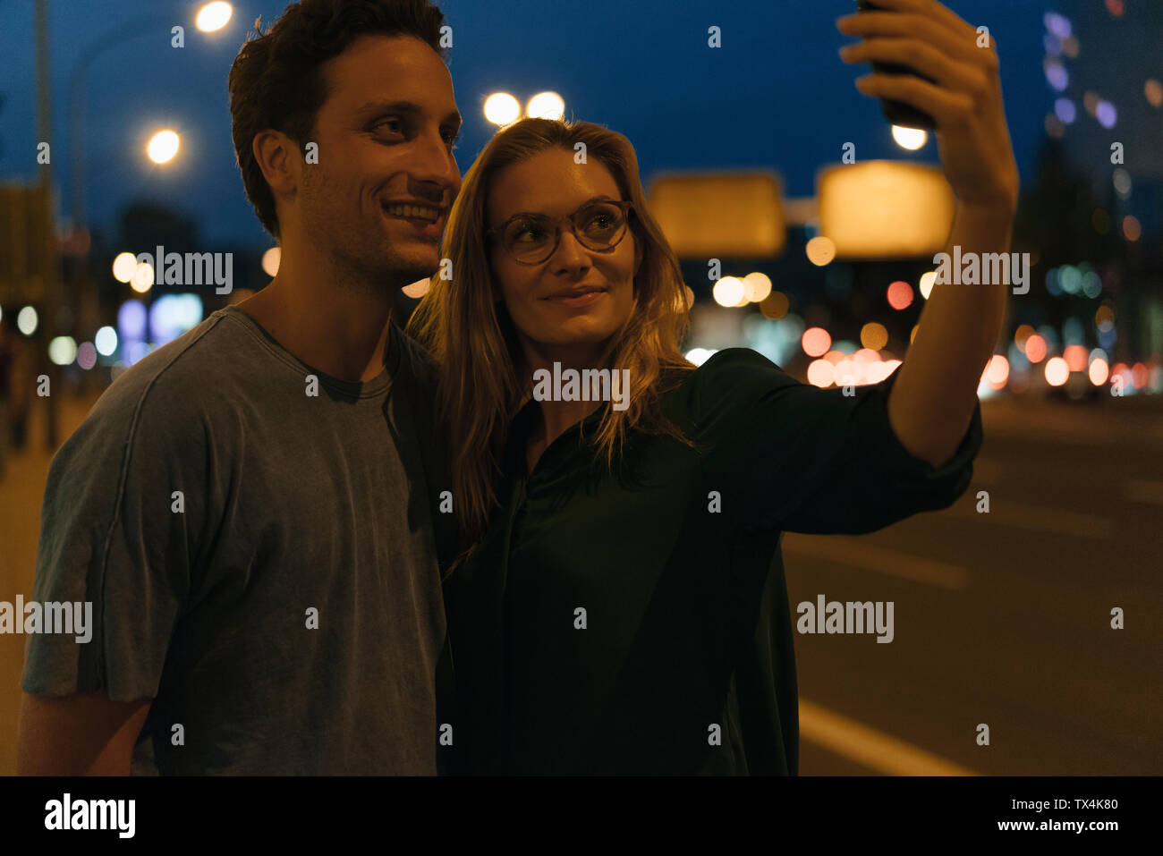 Smiling young couple taking a selfie in the city at night Stock Photo ...