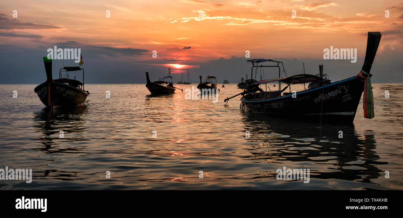 Thailand, Krabi, Railay beach, long-tail boats floating on water at sunset Stock Photo