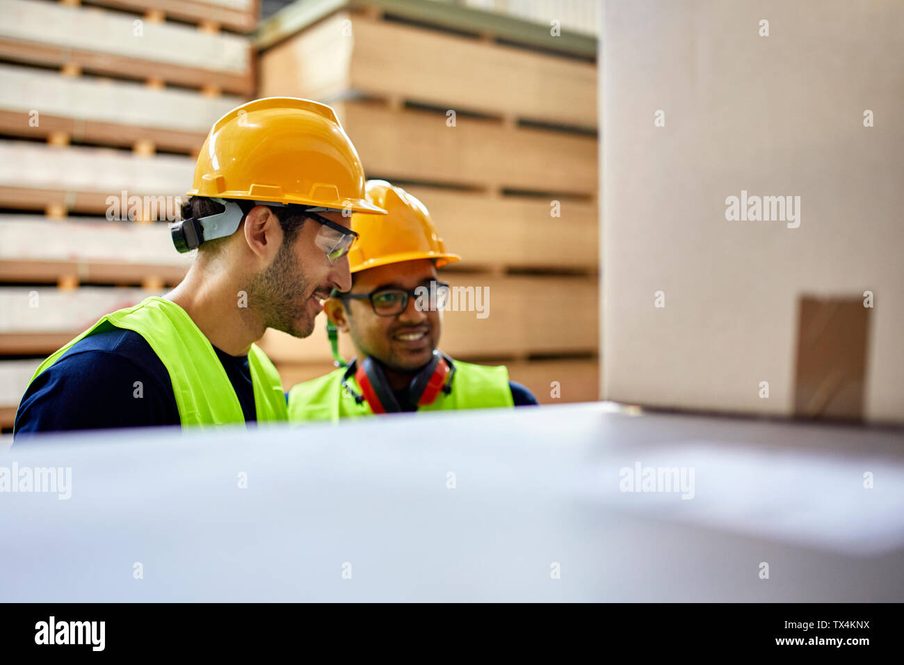 Two workers talking in factory warehouse Stock Photo