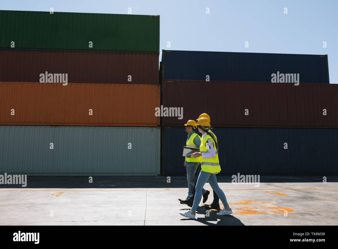 Workers walking together near stack of cargo containers on industrial ...