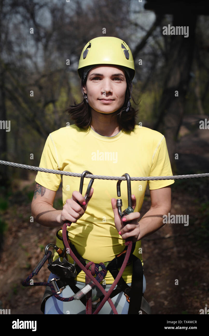 Young woman wearing yellow t-shirt and helmet in a rope course Stock Photo