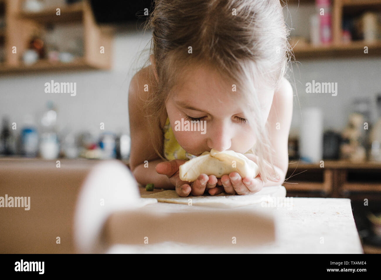 Little girl smelling freshly prepared stuffed pastry Stock Photo