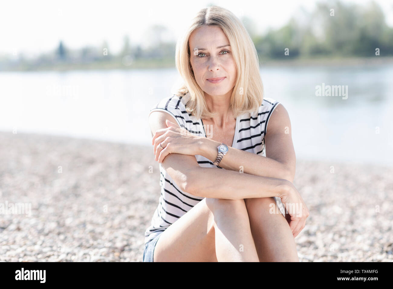 Portrait of smiling mature woman sitting at the riverside Stock Photo ...