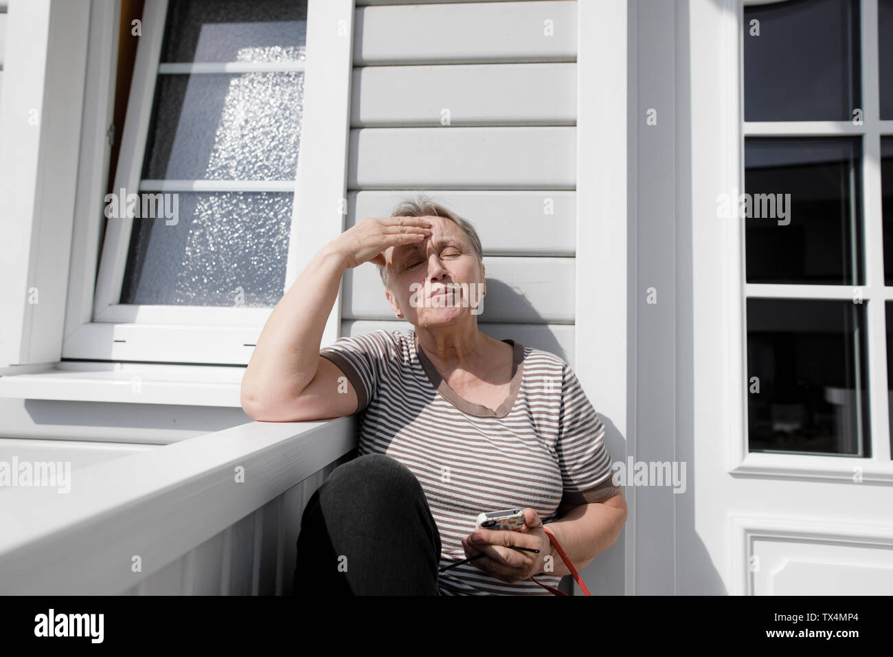 Relaxed senior woman sitting on porch in sunshine Stock Photo - Alamy