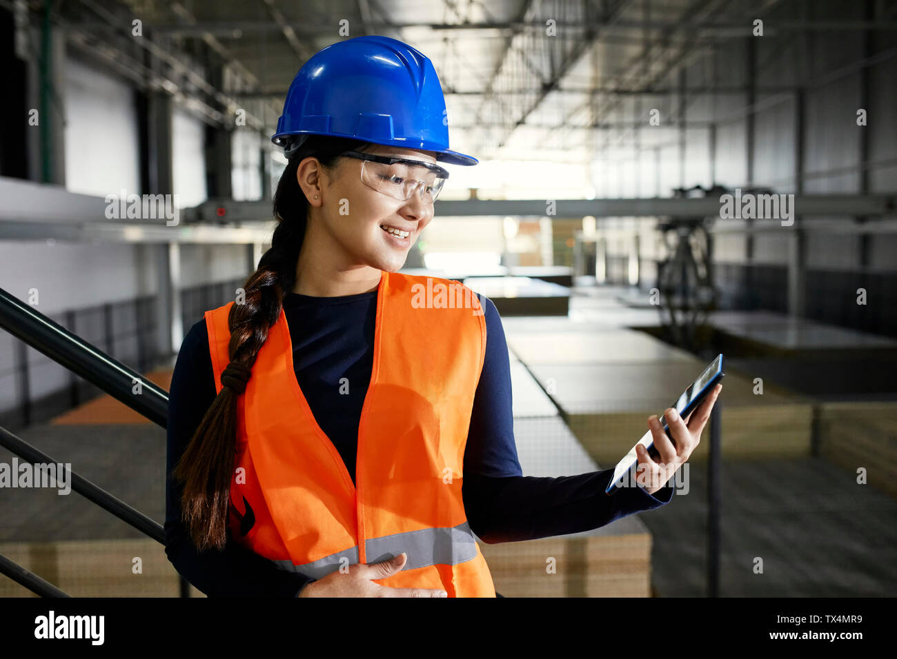 Smiling female worker using tablet in factory warehouse Stock Photo