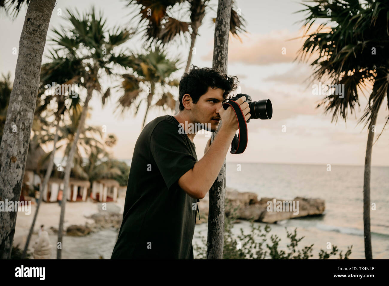 Mexico, Quintana Roo, Tulum, young man taking pictures on the beach Stock Photo