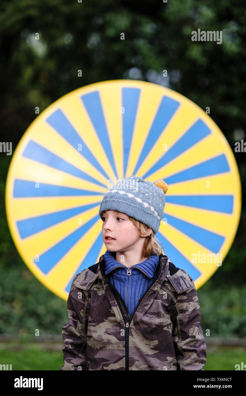 Portrait of boy wearing warm clothing standing in front of yellow and blue circle Stock Photo