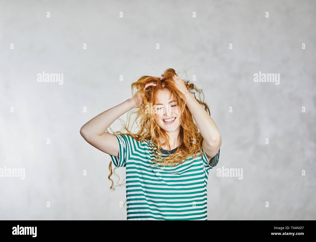 Portrait of redheaded young woman with hands in hair Stock Photo