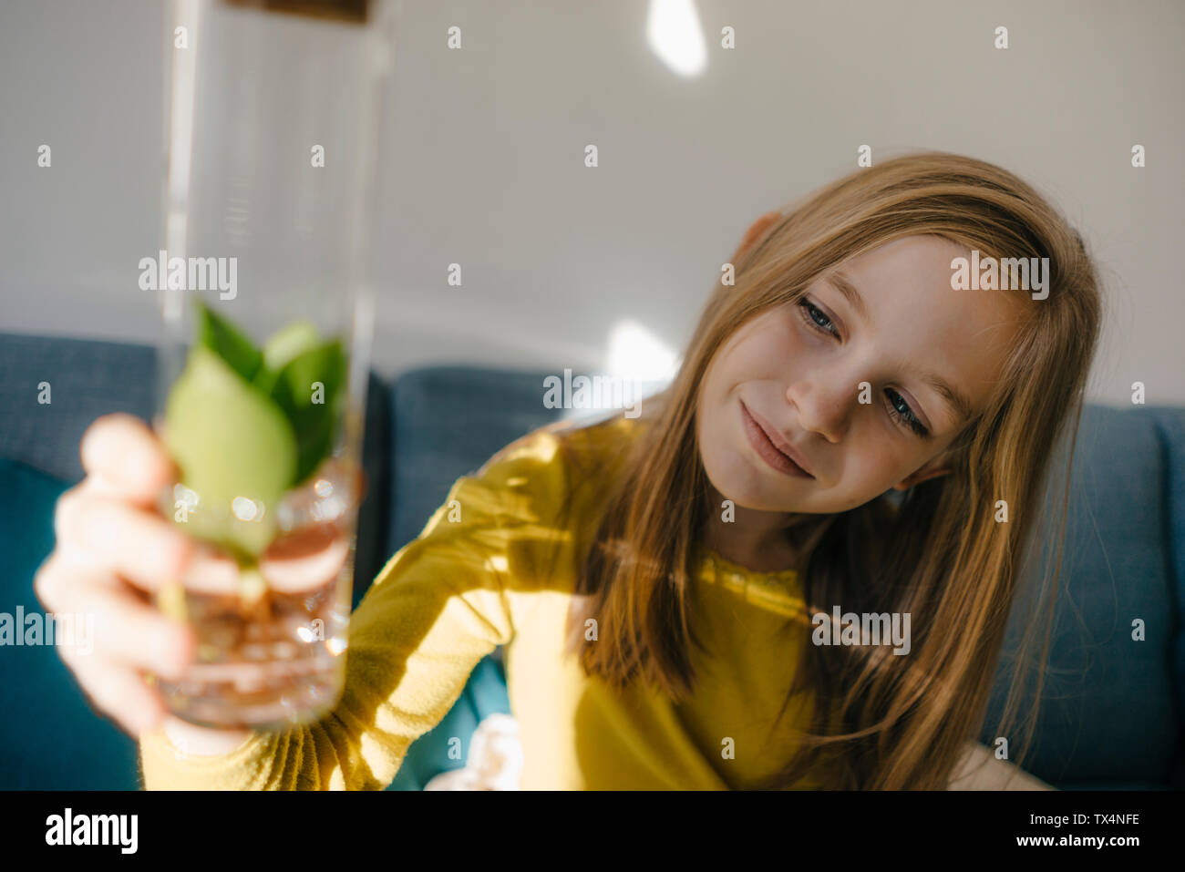 Girl at home looking at plant in a glass Stock Photo