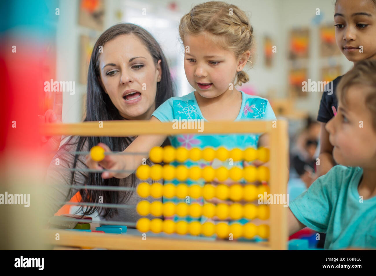 Pre-school teacher with children in kindergarten using abacus Stock Photo