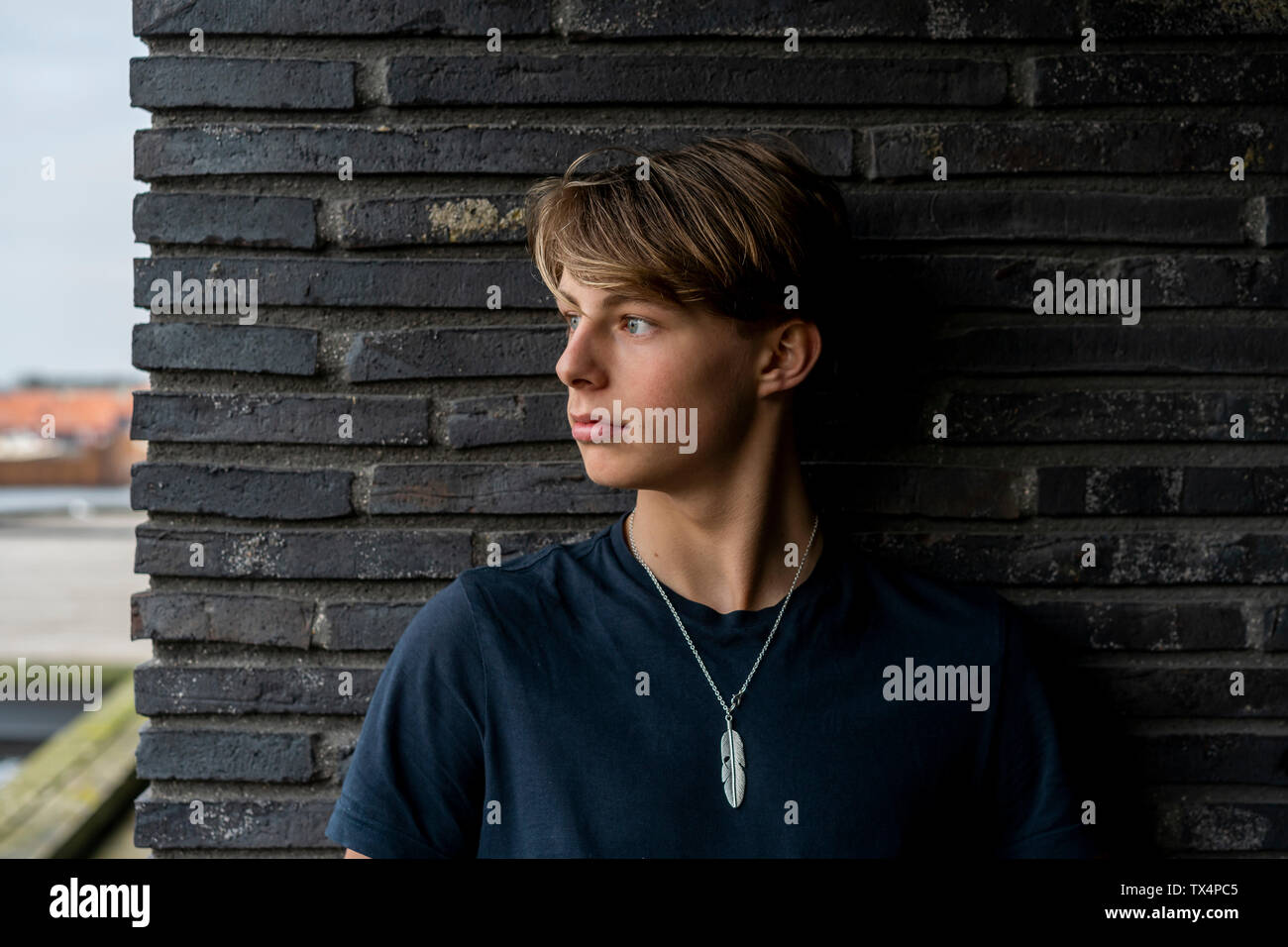 Portrait of young man leaning against a wall Stock Photo - Alamy