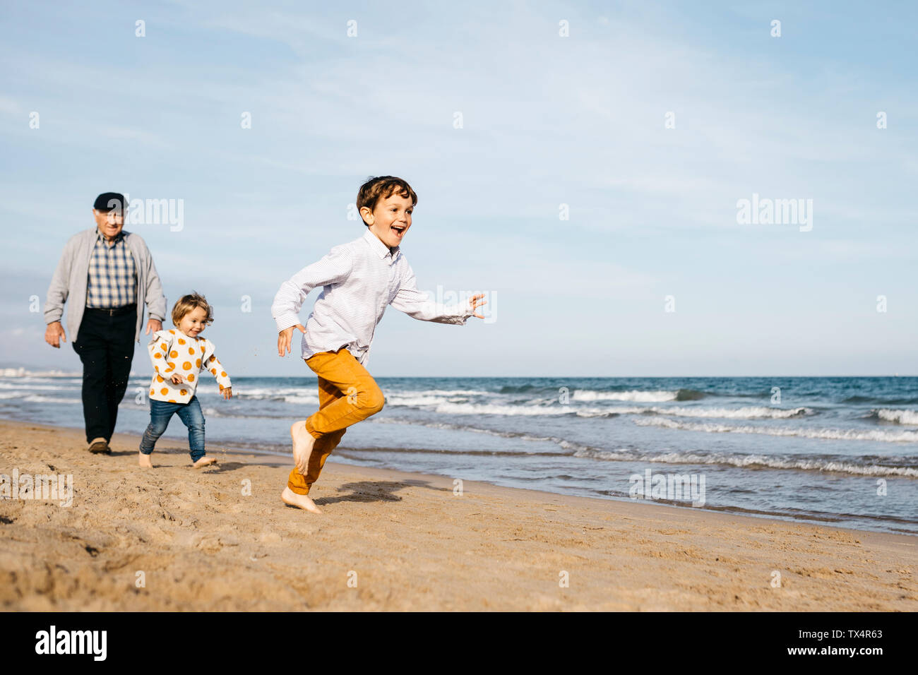 Grandfather strolling with his grandchildren on the beach Stock Photo