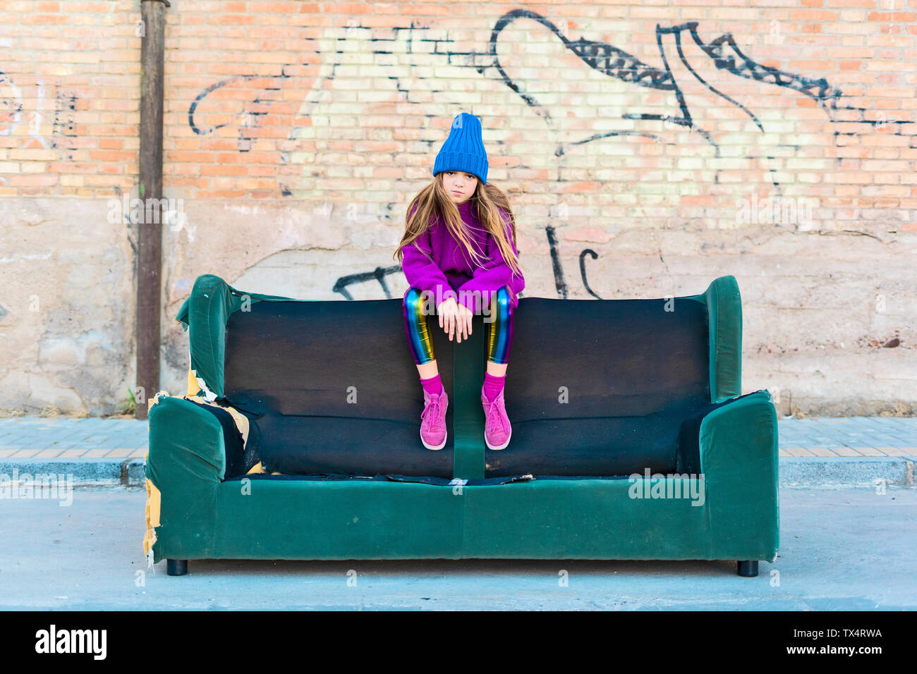 Girl Wearing Colorful Clothing And Sitting On A Couch Outdoors