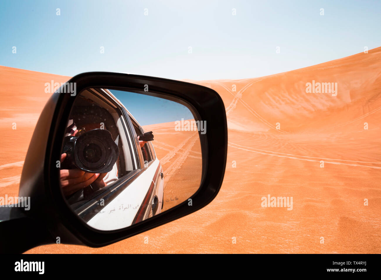Mirror image of a man taking pictures from a off-road vehicle, Oman, Wahiba Sands Stock Photo