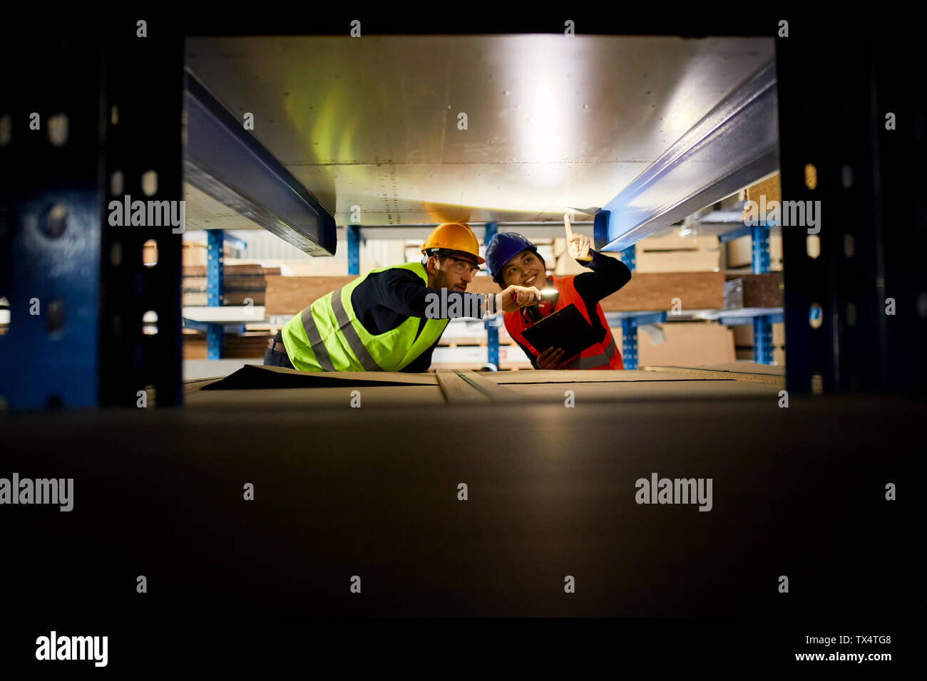 Two workers with torch searching something in factory warehouse Stock