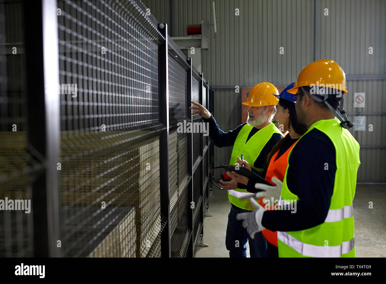 Workers standing at grid in factory talking Stock Photo - Alamy