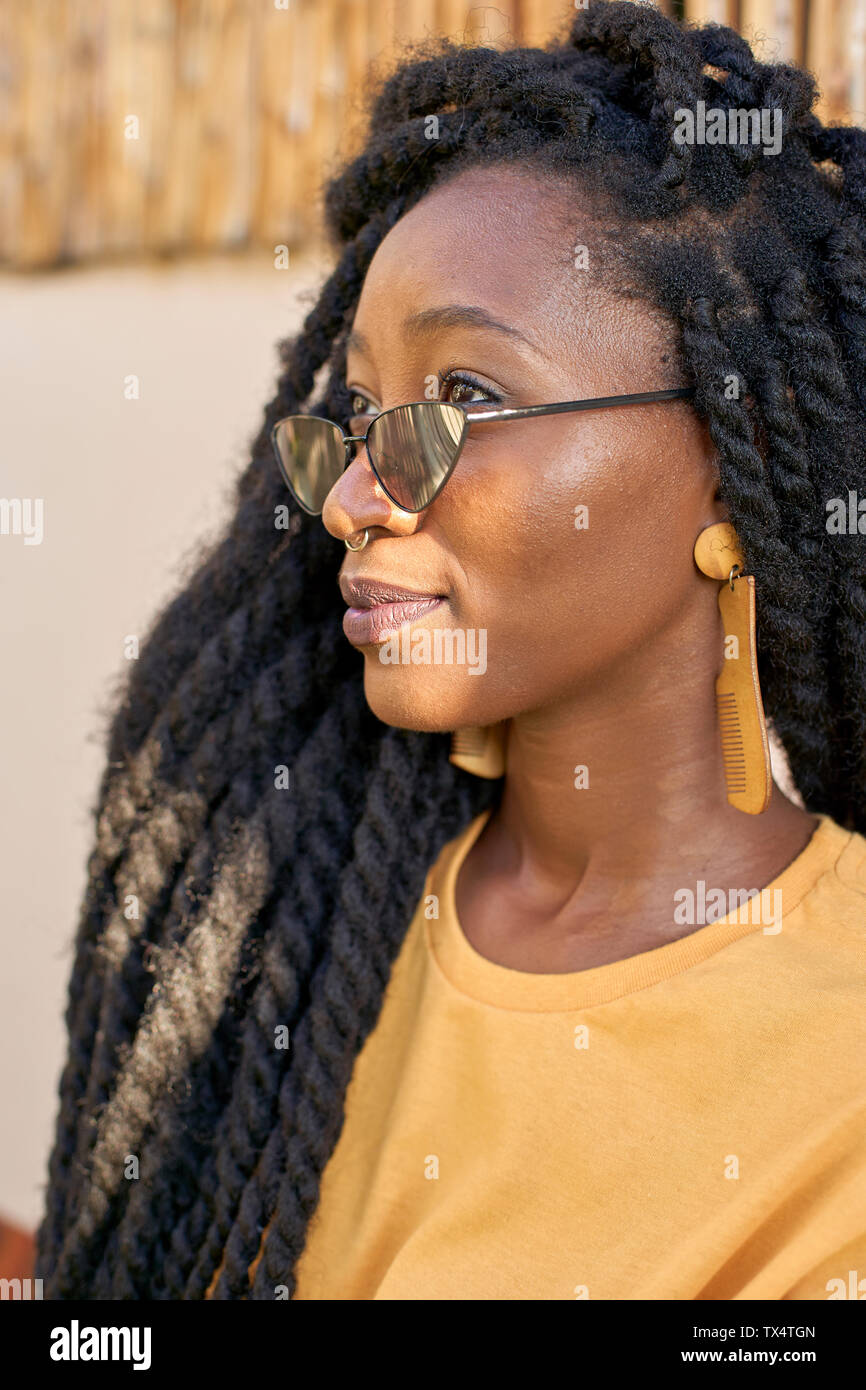 Portrait of young woman with nose piercing, sunglasses and dreadlocks Stock Photo