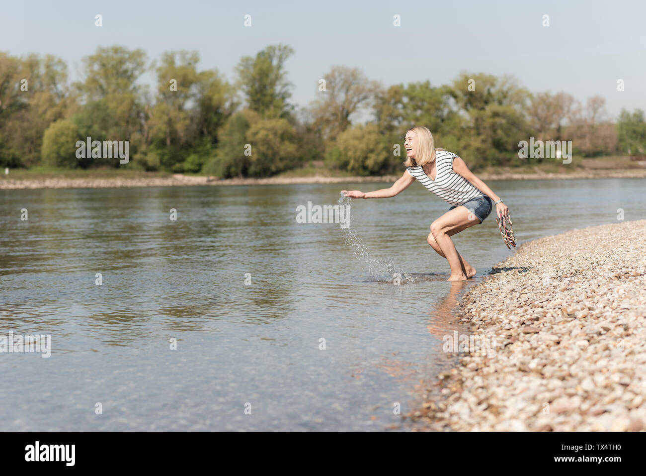 Happy mature woman splashing in a river Stock Photo - Alamy