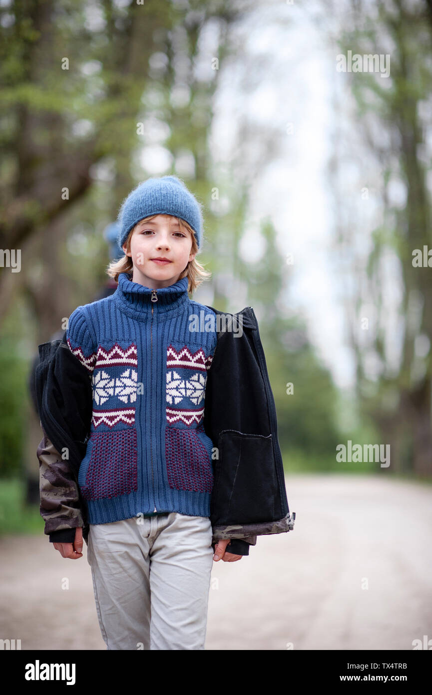Portrait of young boy wearing blue hat and sweater in a park Stock Photo